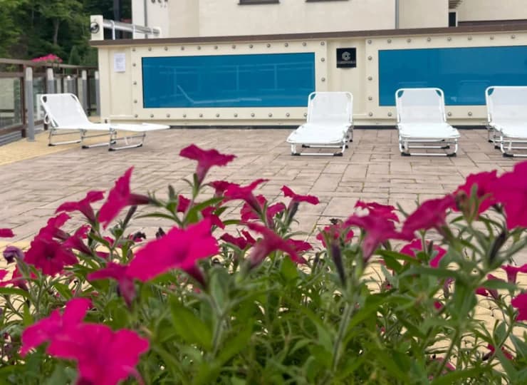 Obok basenu zewnętrznego ustawiono rozkładane leżaki