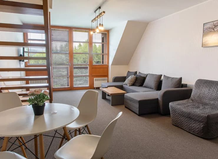 Dwupoziomowy pokój ma na dole salon z rozkładaną kanapą