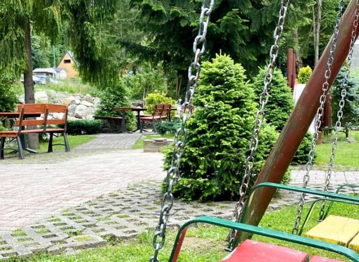 W zadbanym ogrodzie przygotowano plac zabaw ze zjeżdżalnią, huśtawką itp