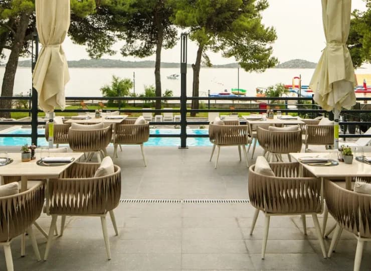 Obok basenu jest restauracyjny taras ze stolikami