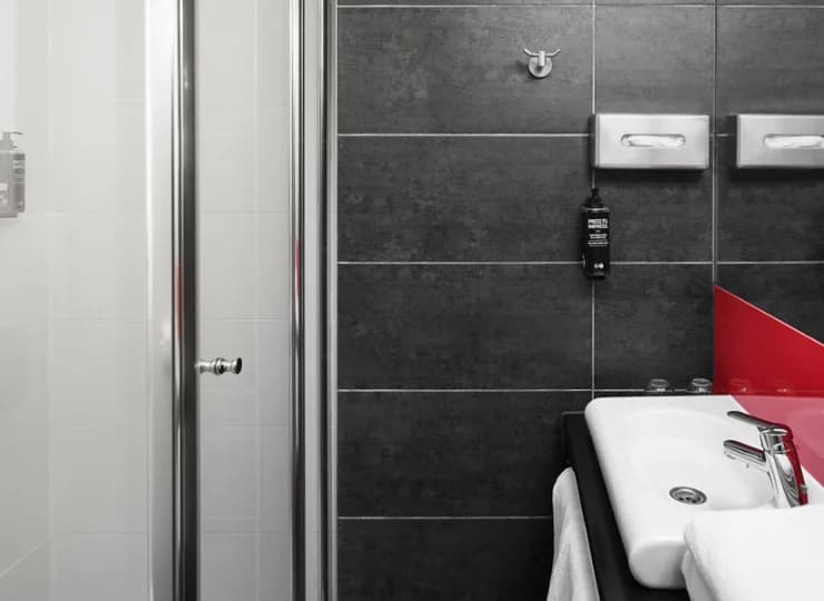 W łazience z prysznicem znajdują się ręczniki, kosmetyki oraz suszarka