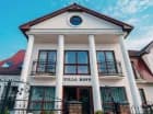 Pokoje hotelowe mieszczą się w eleganckim budynku, za nim kompleks domków